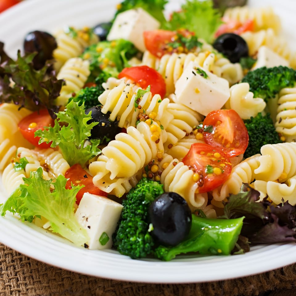 Close-up of Zaca Salad's pasta salad with tomatoes, olives, broccoli, feta, and greens.
