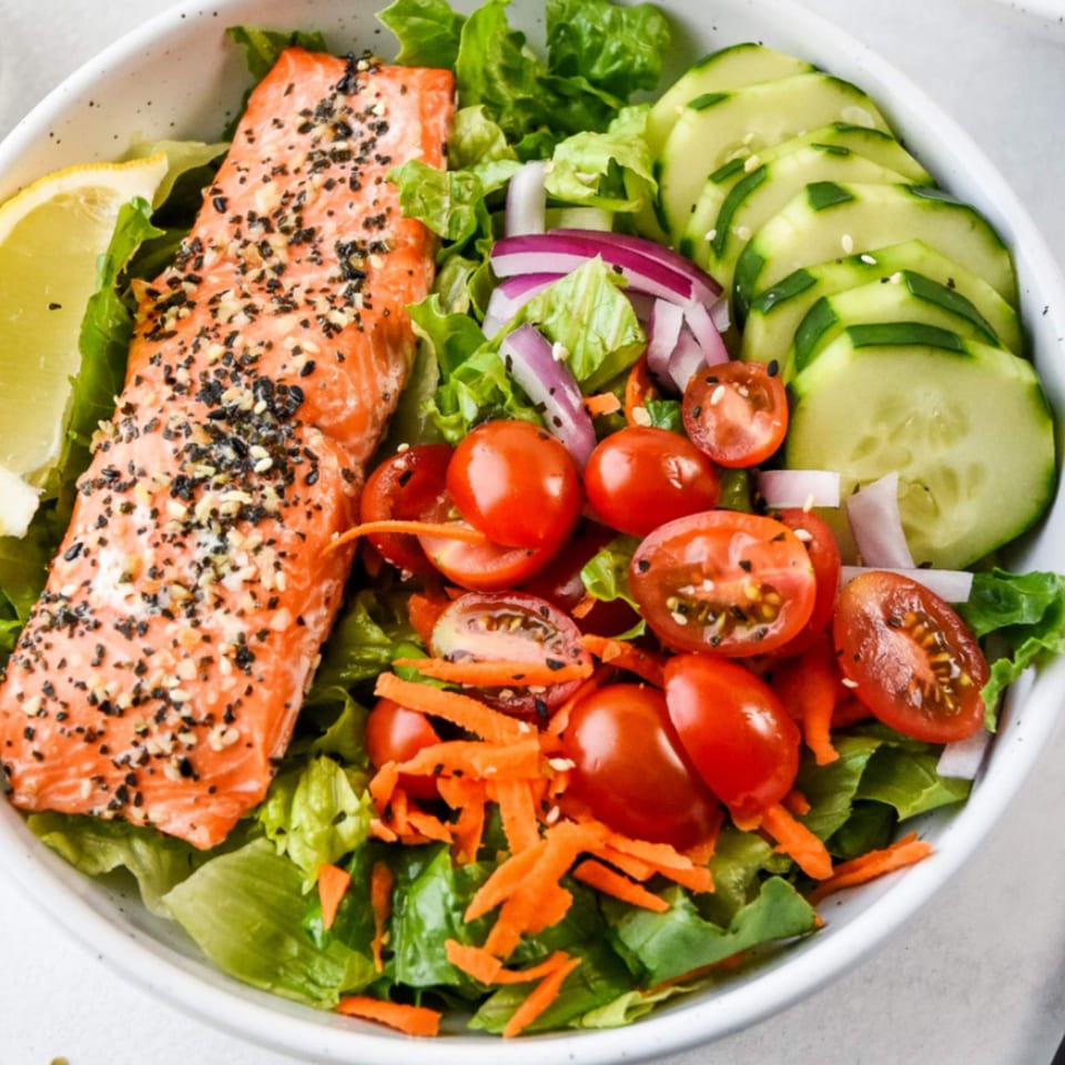 Zaca Salad with salmon, lettuce, cherry tomatoes, cucumbers, red onion, and shredded carrots.